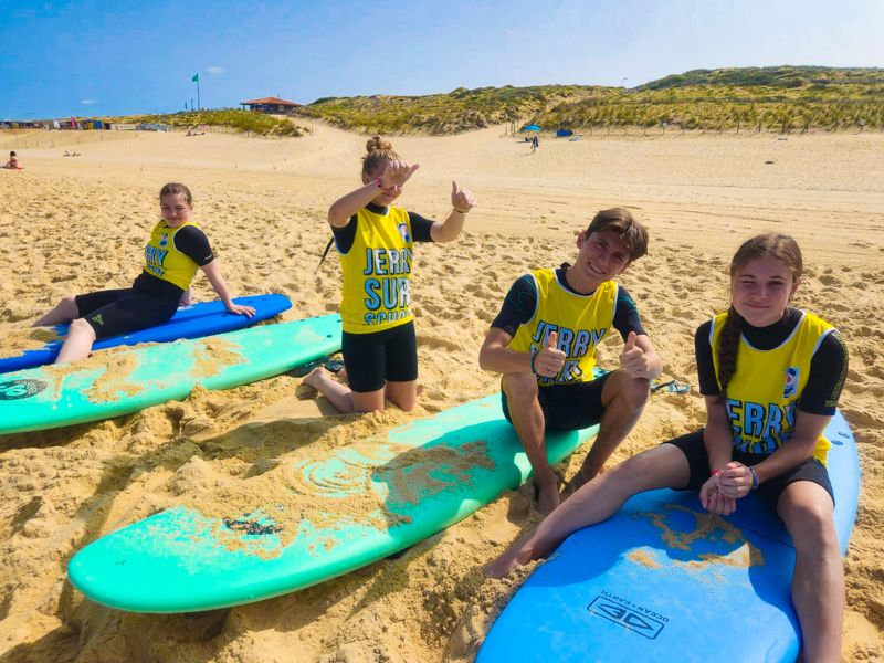 Groupe d'ados qui s'entraine à faire du surf en colo de vacances cet été à l'océan 