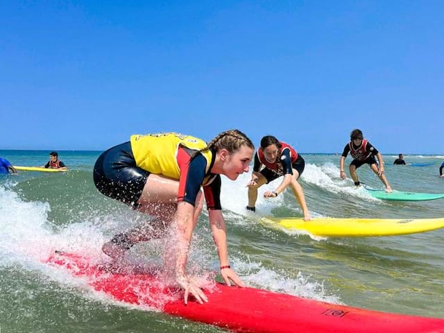 Ado qui réussit à se lever de sa planche de surf cet été en colo de vacances à l'océan 