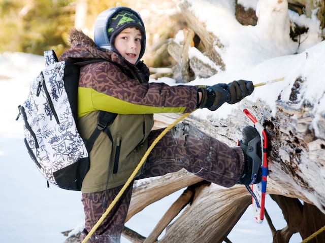 Enfant qui chausse ses raquettes à neige en colo