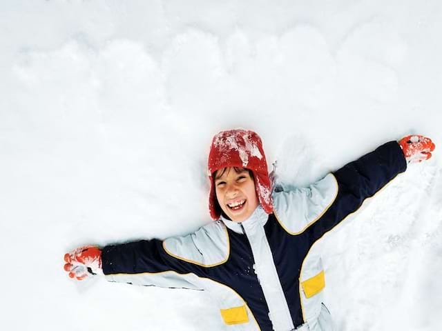 Enfant allongé dans la neige en colonie de vacances