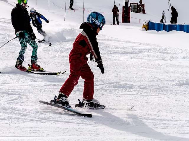 Enfant apprenant à skier à la montagne en colonie de vacances