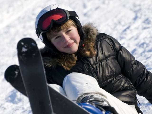 Enfant dans la neige avec ses skis en colonie de vacances