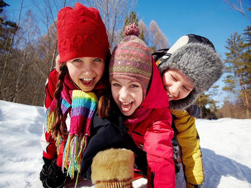 trois enfants en colonie de vacances s'amusant dans la neige cet hiver