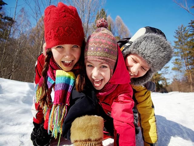 trois enfants en colonie de vacances s'amusant dans la neige cet hiver