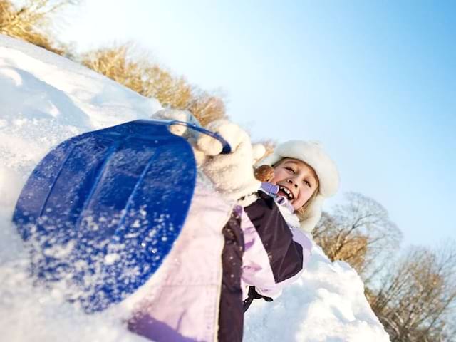 fillette faisant de la luge en colo cet hiver