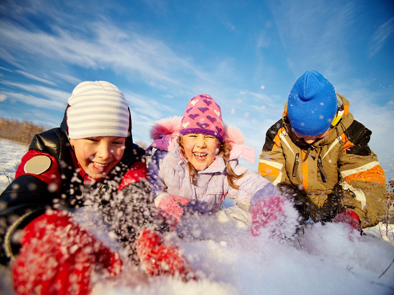 trois enfants jouant avec la neige durant une colonie de vacances cet hiver