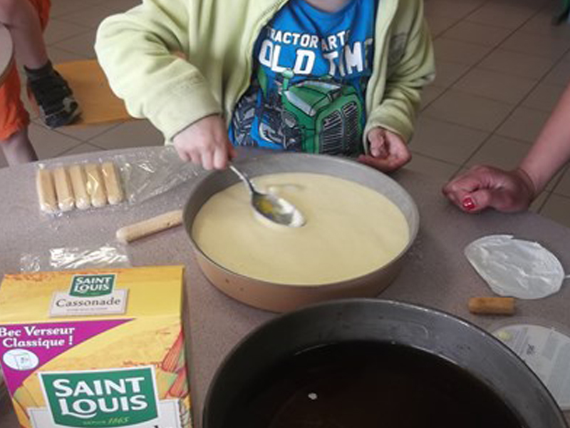 Enfant en train de faire un gâteau en colo