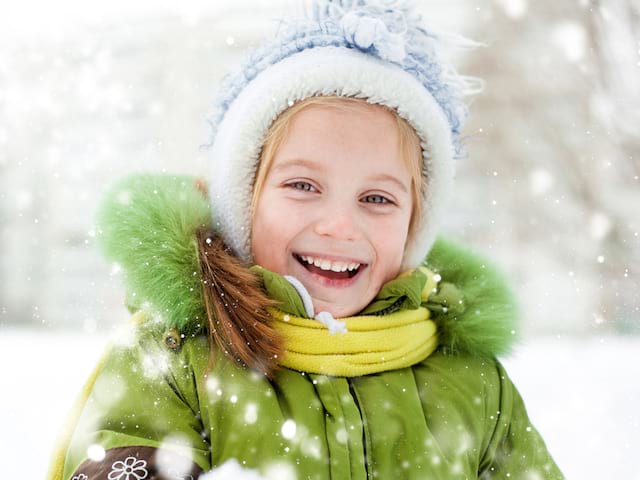 Petite fille blonde souriante sous la neige