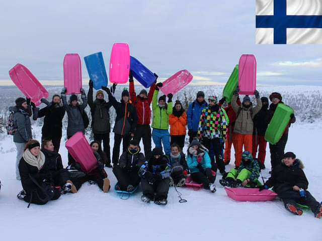 Groupe de jeunes en colonie de vacances en luge en Laponie