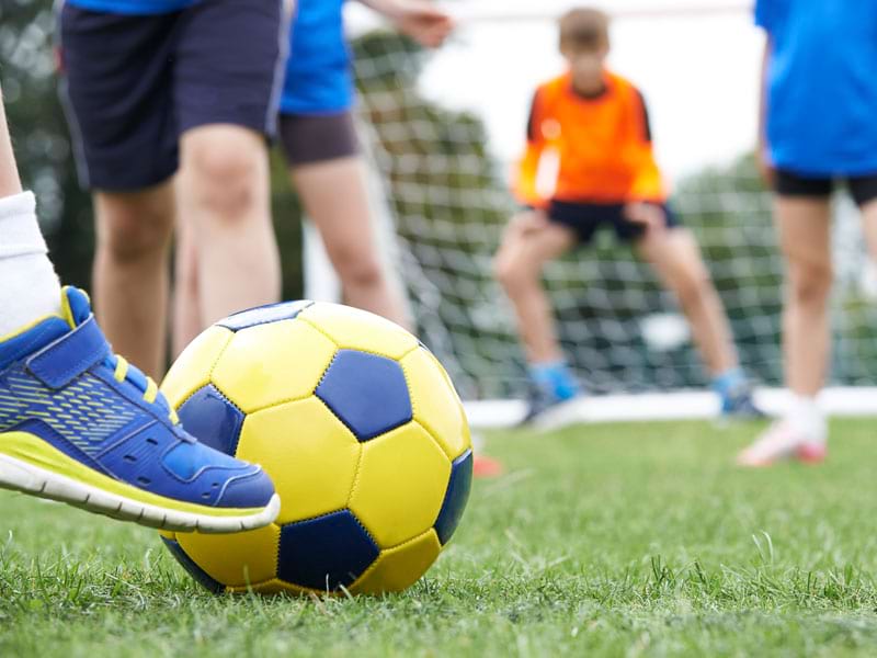 Enfant jouant au football en colonie de vacances sportive