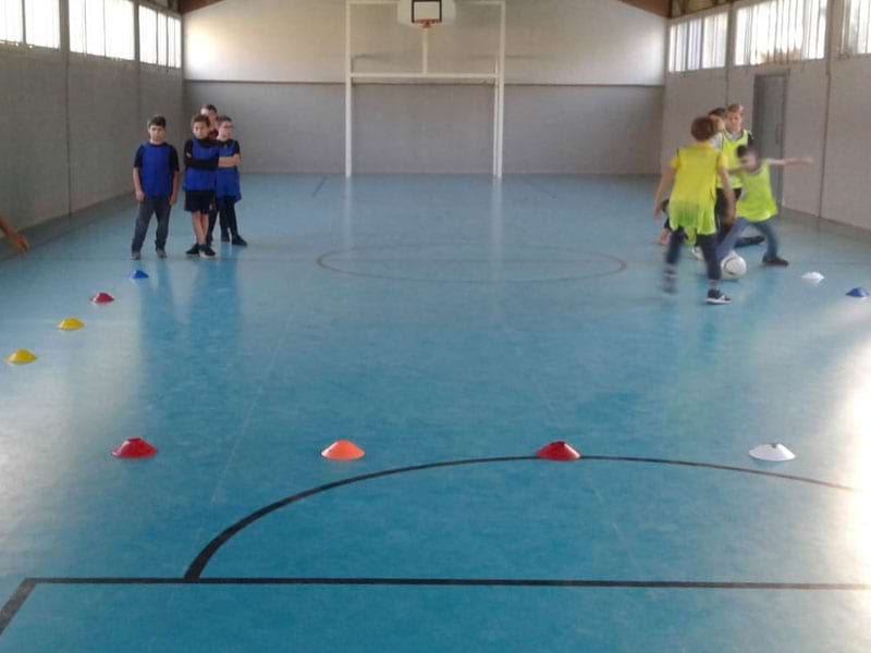 Enfants pratiquant le football en colonie de vacances sen gymnase