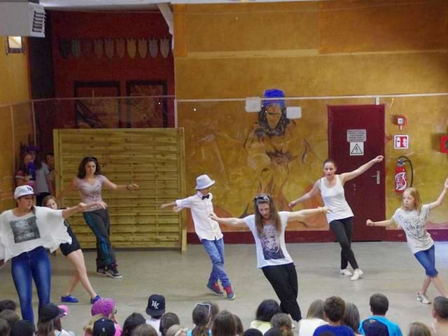 Groupe d'ados dansant devant d'autres enfants en colonie de vacances artistique