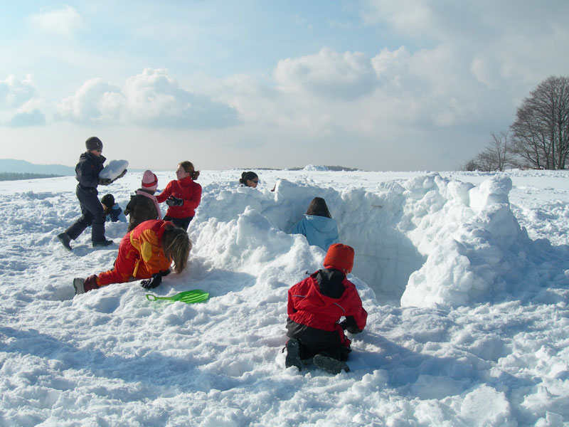 groupe d'enfants en colonie de vacances en train de construire un igloo