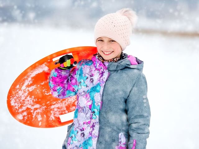 fillette avec sa luge en colonie de vacances au ski