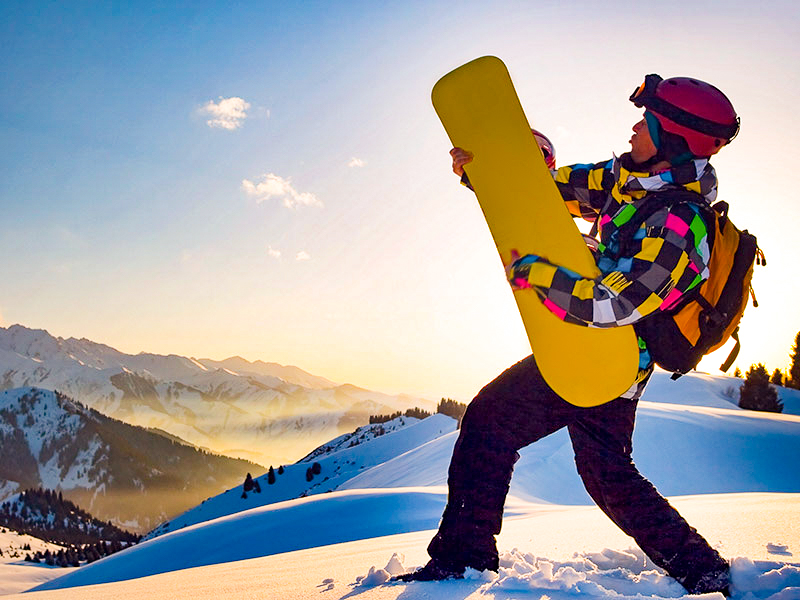 Ado avec sa planche de snowboard en colo cet hiver
