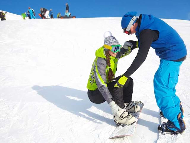 Ado qui apprend le snowboard avec un moniteur de ski