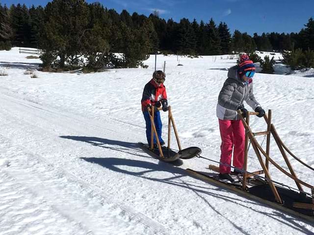 Deux enfants sur un traineau en colo cet hiver