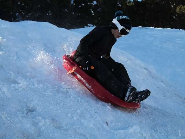 Enfant s'appretant à glisser à luge en colonie de vacances