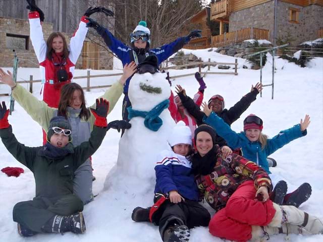 Groupe d'enfants heureux devant leur bonhomme de neige en colonie de vacances