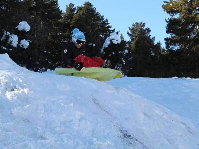 Enfant de 8 ans faisant des glissades à luge dans la neige en colonie de vacances