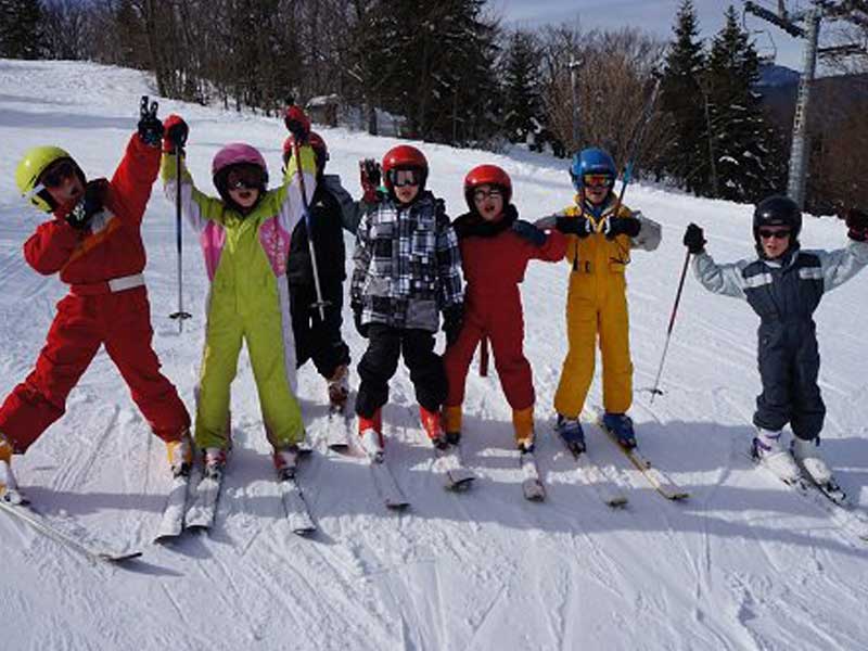 Skieurs débutants en colonie de vacances qui apprennent le ski avec des moniteurs ESF