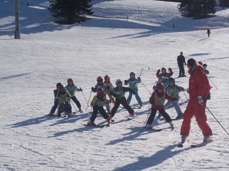 Groupe de jeunes skieurs débutants qui s'exercent sur les pistes en colo