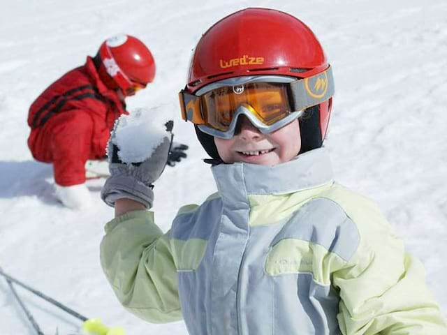 Jeune enfant en colo de vacances qui fait des boules de neige