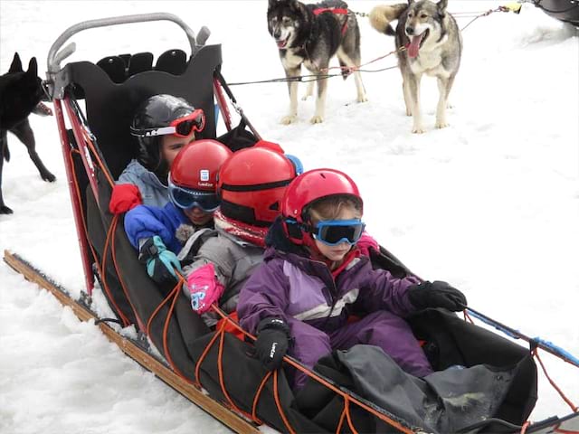 Enfants sur un traineau en colonie de vacances cet hiver