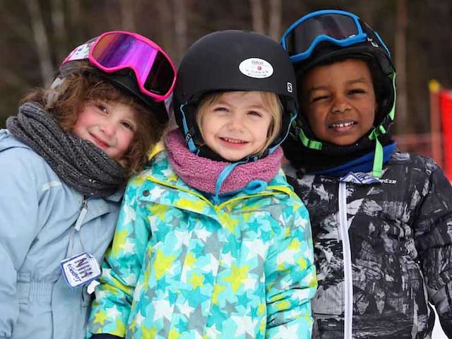 Portrait de trois enfants en colonie de vacances cet hiver sur les pistes de ski