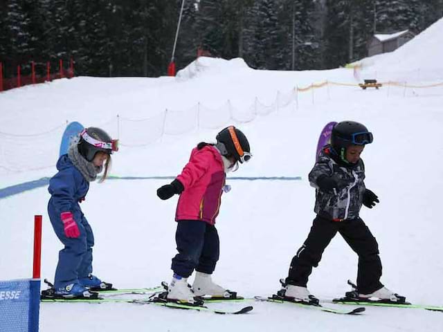 trois enfants apprenant à faire du ski en colo cet hiver