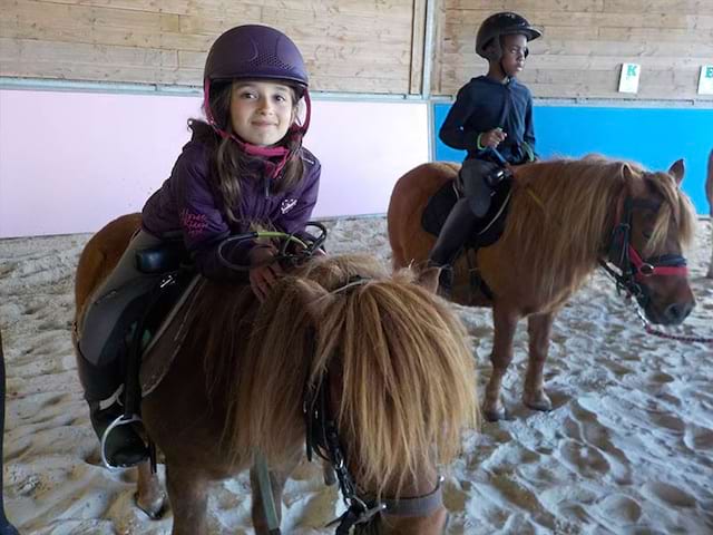 Enfants montant à poney en colonie de vacances d'hiver