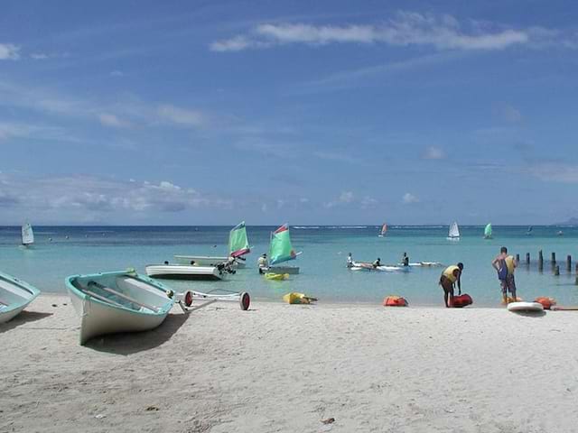 Vue sur le bord de plage avec des bateaux et un grand soleil bleu lors d'une colo de vacances en Guadeloupe durant l'hiver