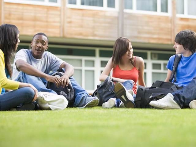 Groupe d'amis discutant dans l'herbe lors de leur colo de vacances à Malte