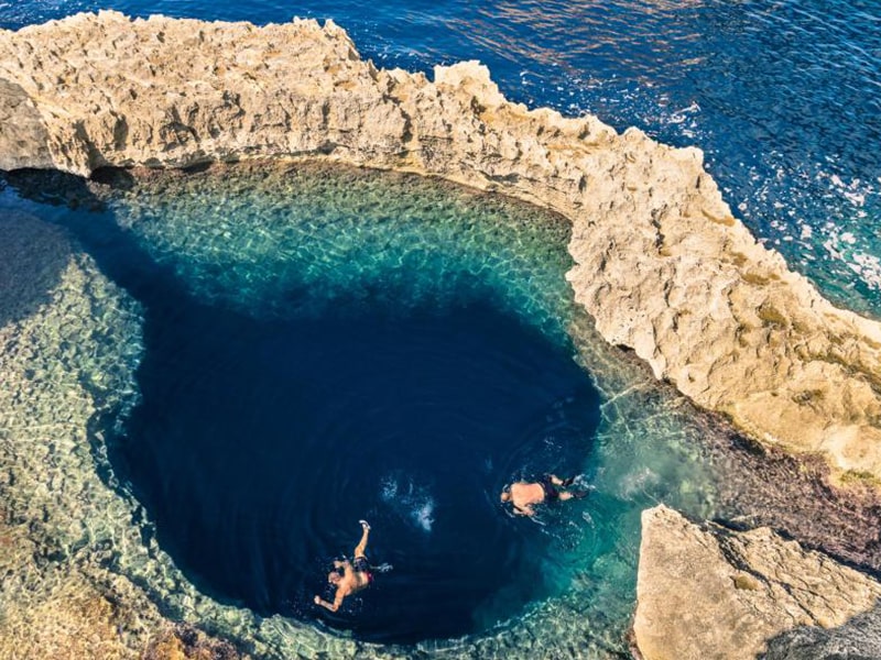 Vue en plongée sur le lagon avec des baigneurs et une eau bleu turquoise à Malte lors d'une colonie de vacances 