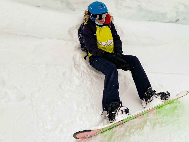 Jeune fille en colo de vacances Ski Sensations qui pratique le snowboard en colonie de vacances cet hiver