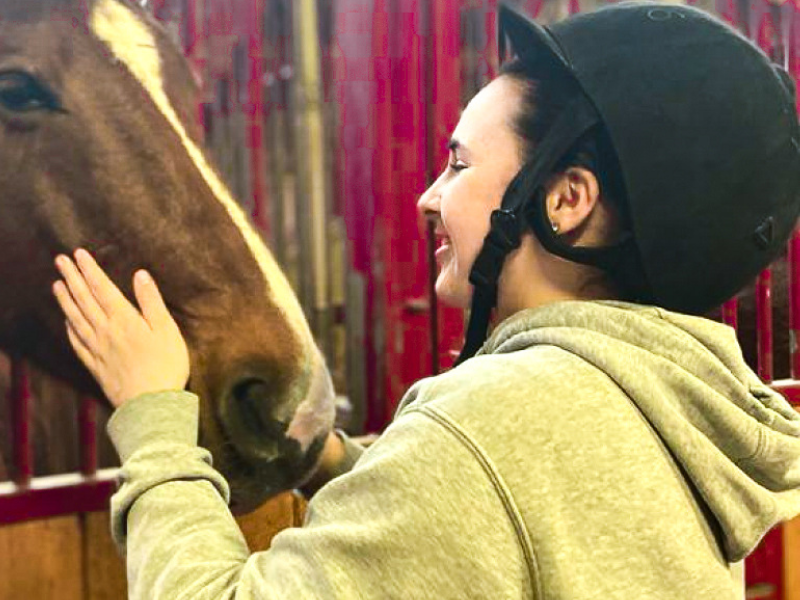 Jeune ado qui s'occupe de son cheval en colo de vacances Equitation cet hiver