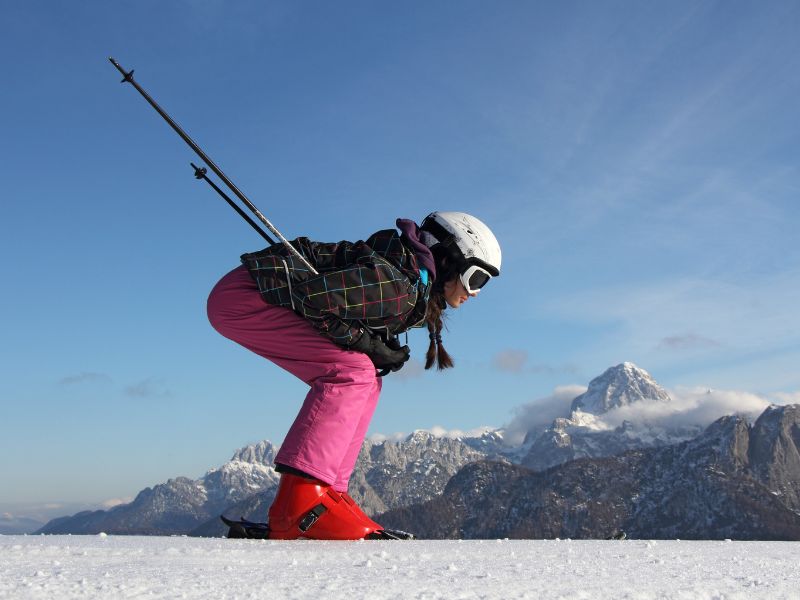 Jeune fille qui dévale les pistes de ski en colo de vacances cet hiver