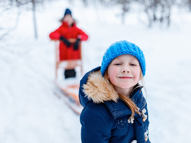enfants jouant dans la neige avec un traineau 