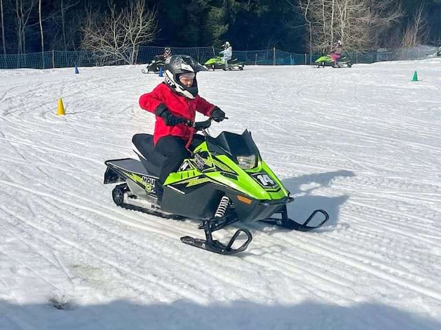 Enfant qui fait de la motoneige cet hiver en colo