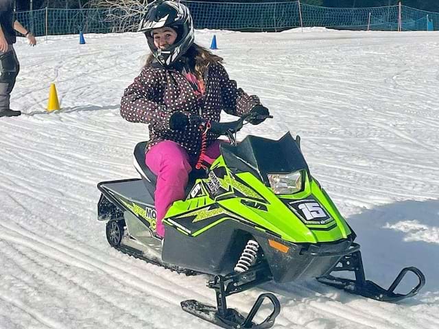 Jeune fille qui s'essaye à la motoneige cet hiver