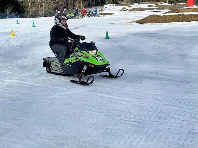 Jeune en colo de vacances qui apprend à faire de la motoneige cet hiver