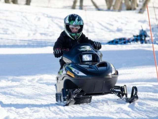 Enfant qui fait de la motoneige en colo de vacances en février