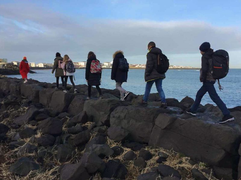 Groupe d'ados marchant en direction d'un village islandais en colo de vacances
