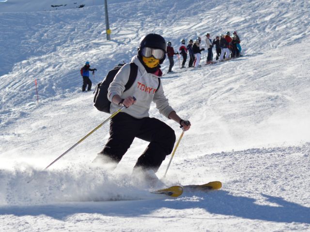 Jeune en cours de ski qui dévale les pistes en colo