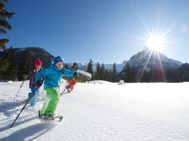 Enfants se déplaçant en raquettes dans la neige en colo