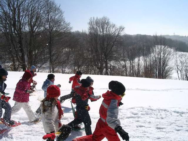 Groupe d'enfants en randonnée raquettes dans la neige