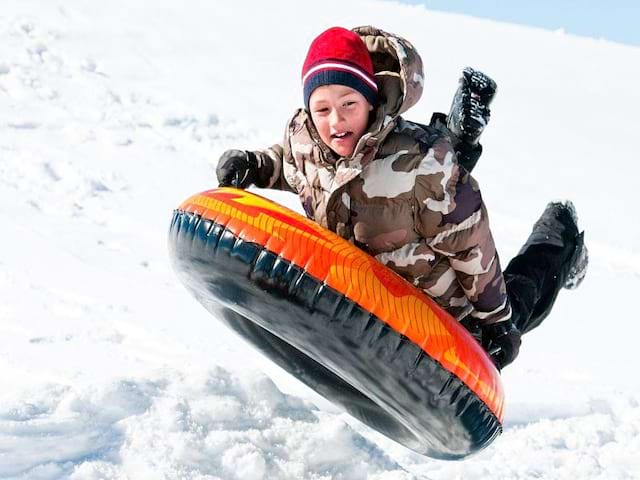 Enfant faisant de la luge gonflable en colonie de vacances cet hiver