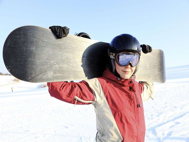 ado portant sa planche de surf des neiges en colo