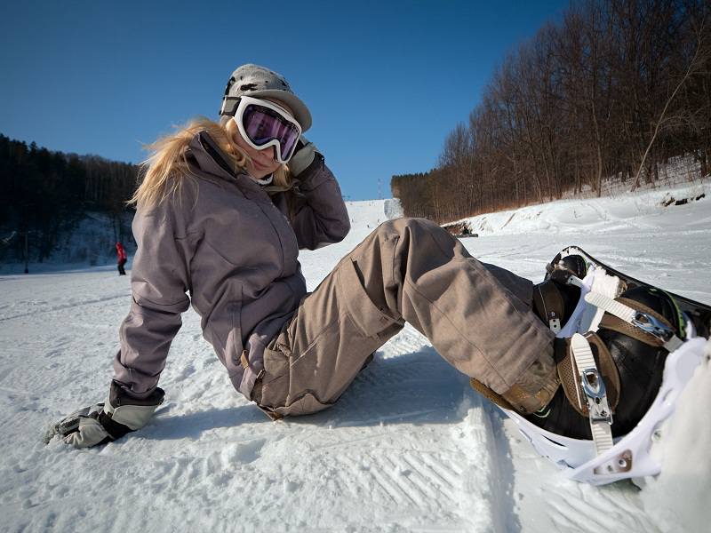 ado assise dans la neige faisant du snowboard cet hiver en colonie de vacances