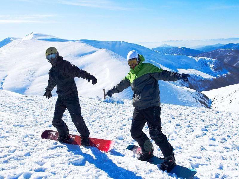 Deux ados faisant du snowboard en colonie de vacances d'hiver